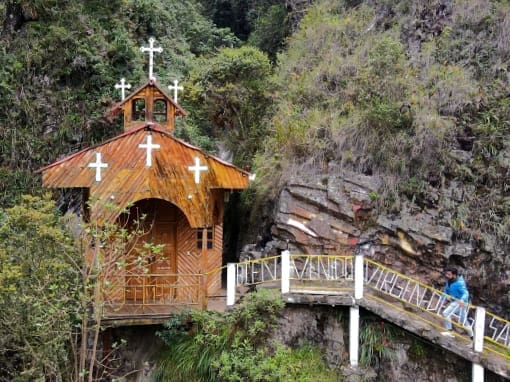 A man walks along a wooden-railed path leading to the Chapel of the Virgin of Holy Water.