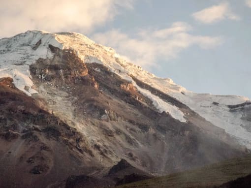 Chimborazo Primer plano del Chimborazo, la montaña más alta de Ecuador, con el sol de la tarde reflejándose en una ladera nevada y de tonos rojo óxido.