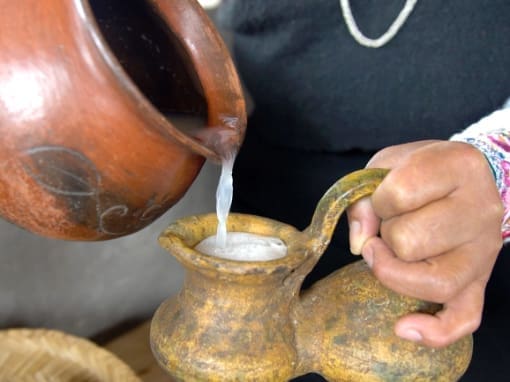 El Guarango A woman's hand holds a clay jar while filling it with guarango, a traditional drink made from agave juice.