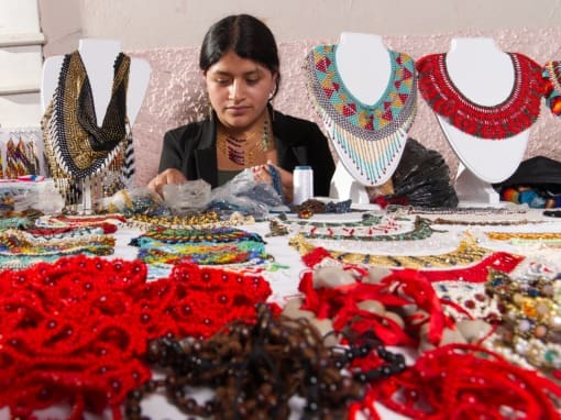 Artisanal jewelry from Saraguro A young Saragura woman sits at her jewelry stall, offering intricately beaded and brightly colored necklaces.